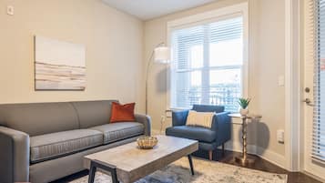 Ein Wohnzimmer mit grauem Sofa, blauem Sofa, Couchtisch und Stehlampe.