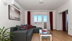 A modern living room with a grey sectional sofa, a glass coffee table, and a potted plant. - Radelic, comfortable two bedroom apartment (Mastrinka)