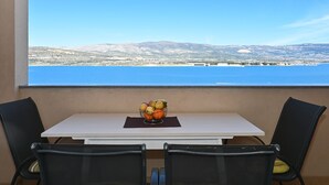 A table with a fruit bowl and two chairs, overlooking a scenic view of a body of water and distant mountains. - Radelic, comfortable two bedroom apartment (Mastrinka)
