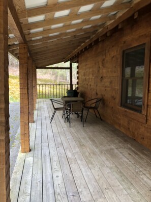 Une terrasse en bois avec une table et des chaises, une fenêtre et une vue sur l’extérieur.