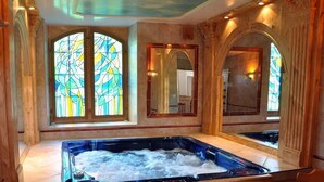 A spa area with a hot tub, large windows with stained glass, and wooden paneling.