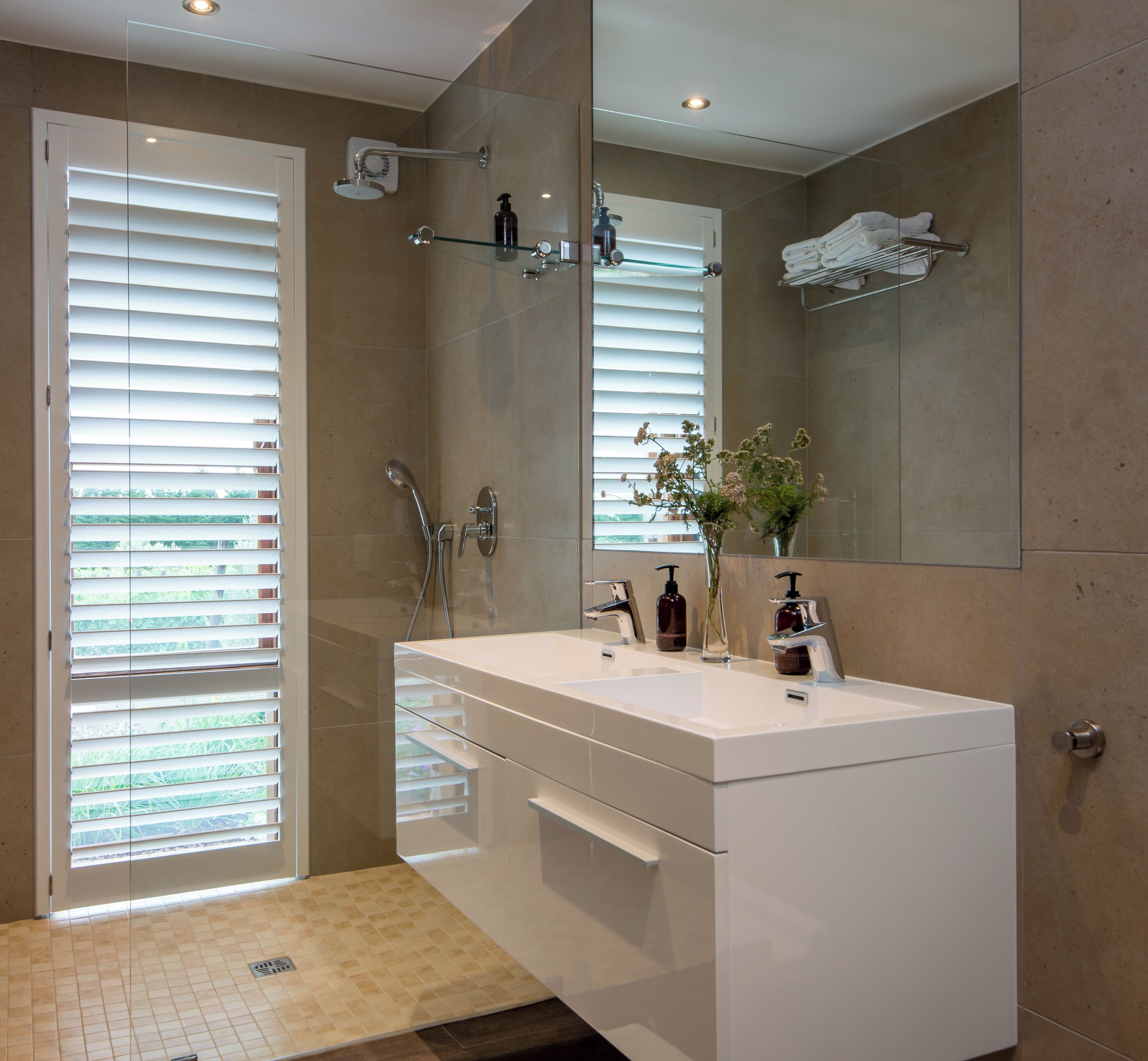 A modern bathroom with a large mirror, white vanity, and a shower area.