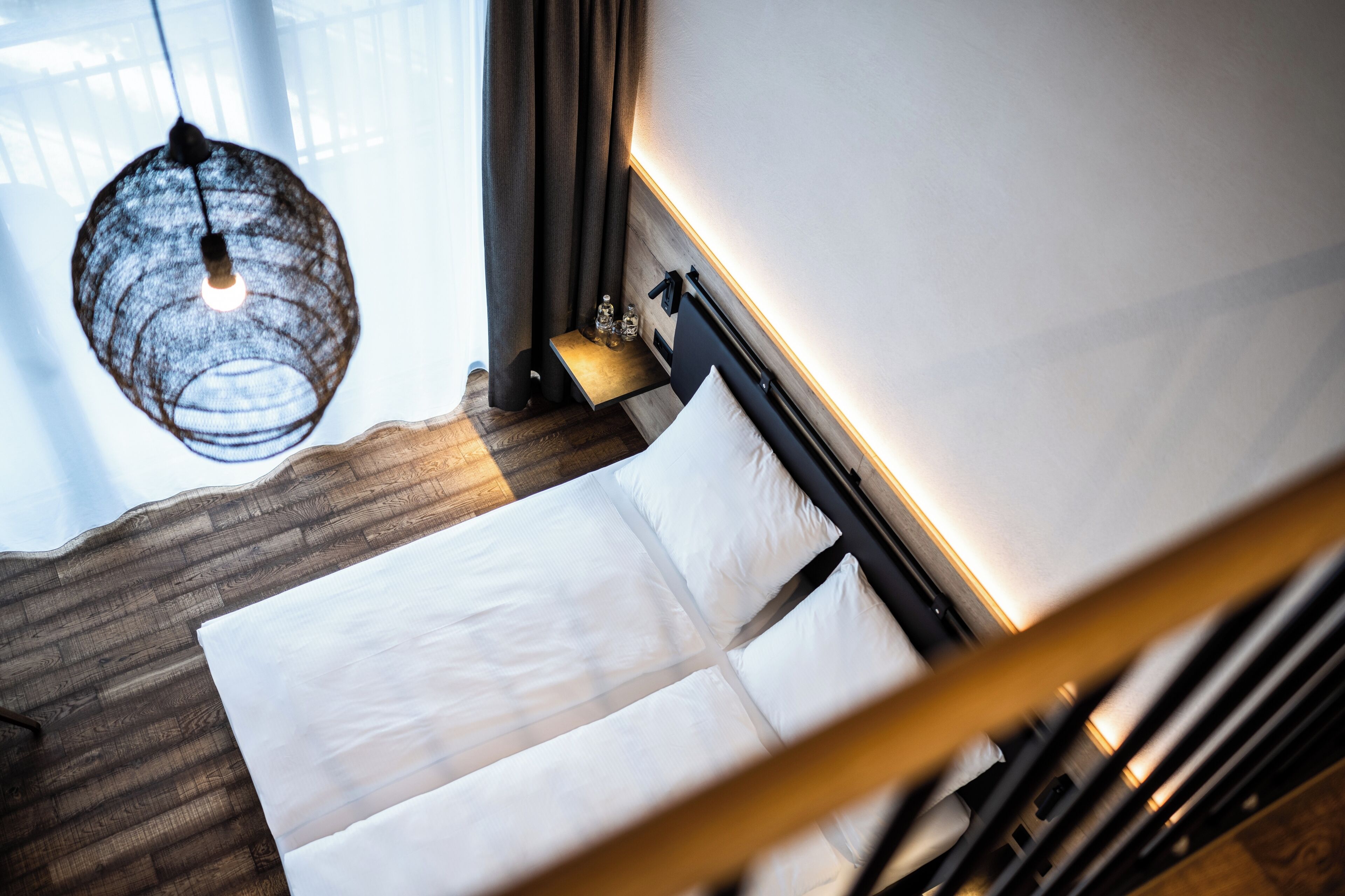Une chambre d’hôtel moderne, équipée d’un lit, d’une table de chevet, d’une lampe et offrant une vue sur l’extérieur.