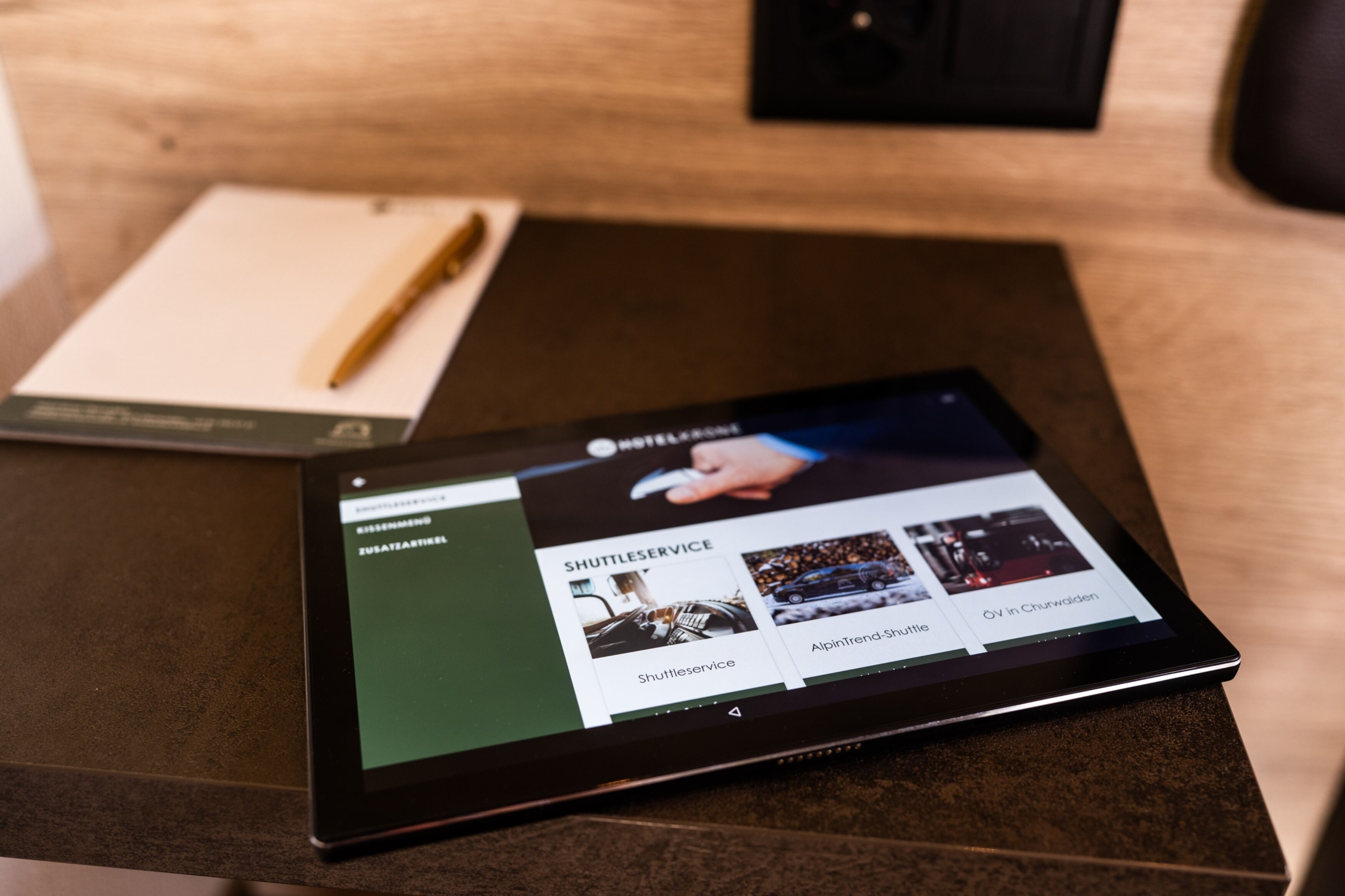 A tablet displaying a hotel website with sections for shuttle service, Alpintrend-Stunde, and a view in the churchyard.