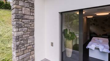 A modern bathroom with a large window, a stone wall, and a potted plant.