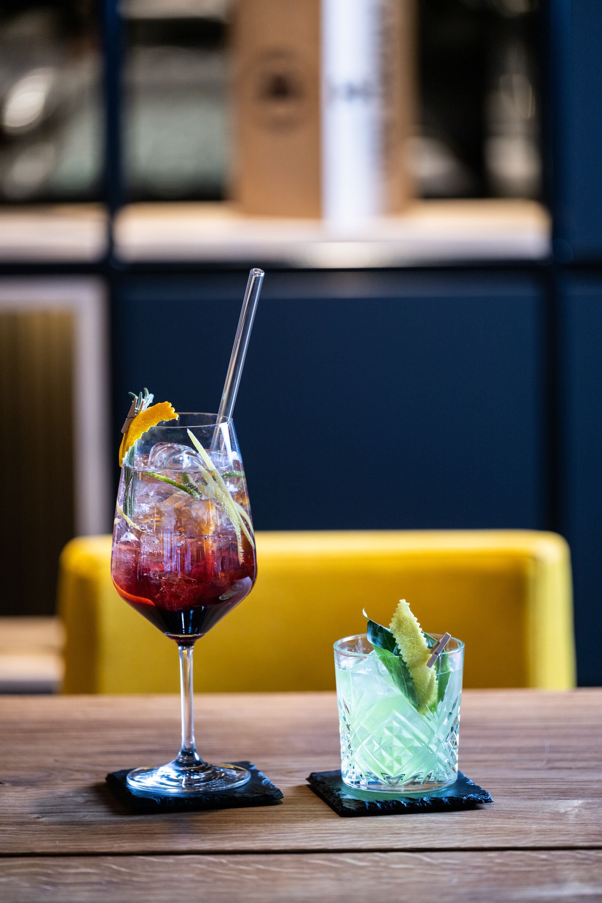 Two drinks on a wooden table with a yellow chair in the background.