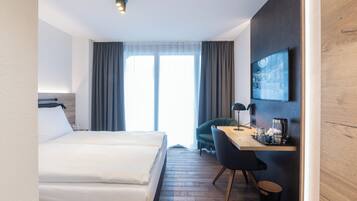 A hotel room with a bed, a desk, a chair, a television, and a window with curtains.