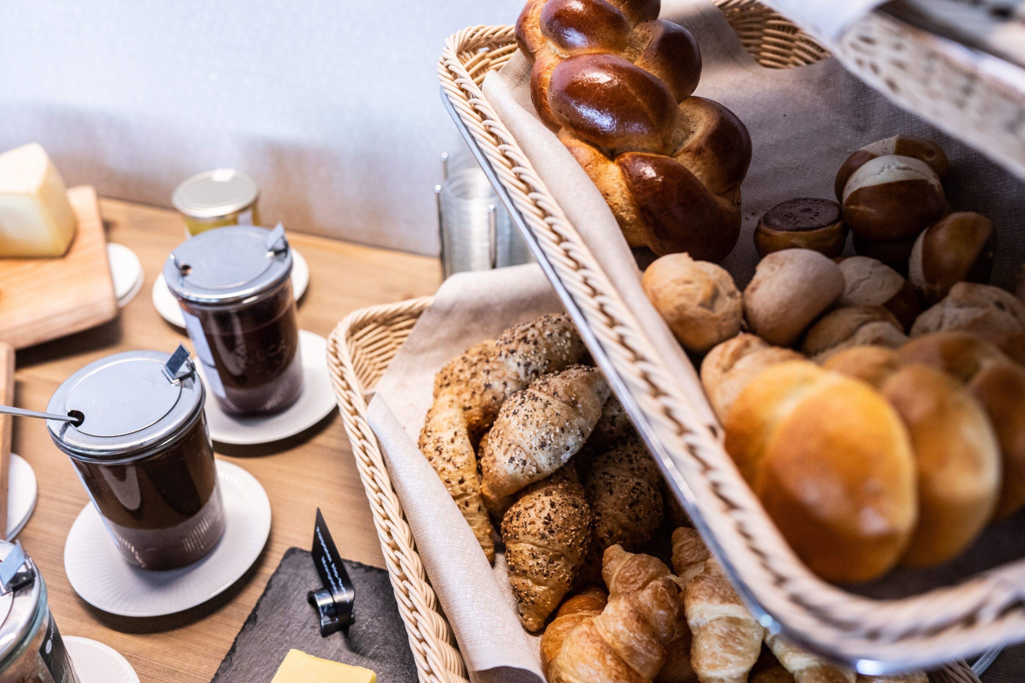 A breakfast buffet with various breads, pastries, and a coffee station.