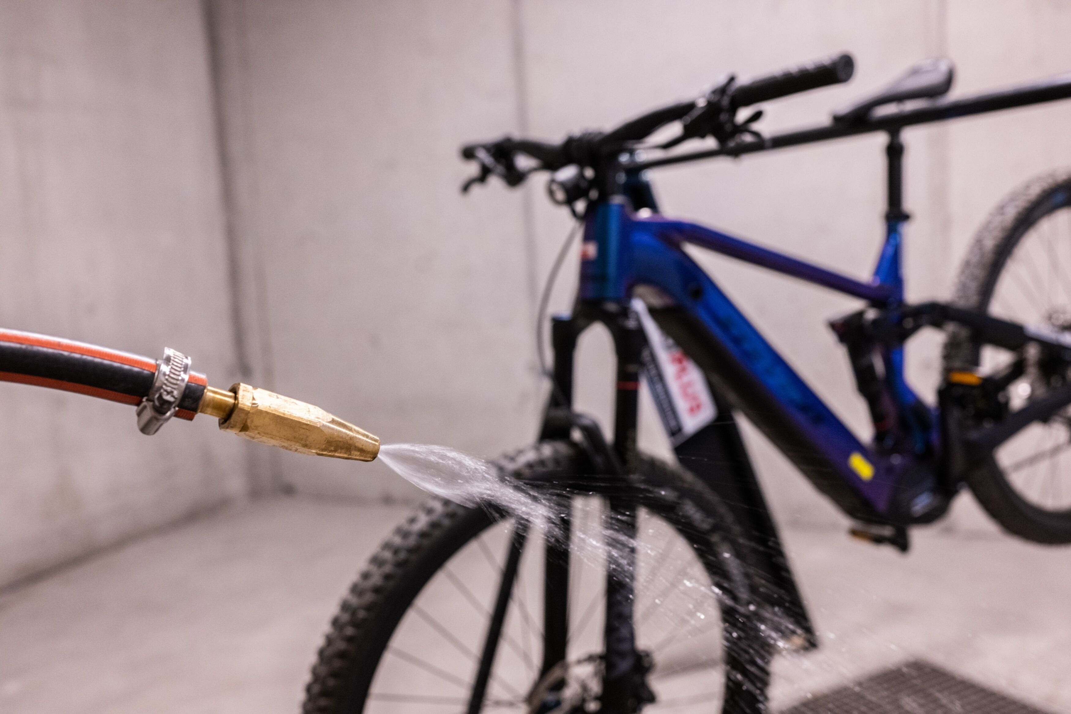 Una bicicleta siendo lavada con una manguera en un garaje.