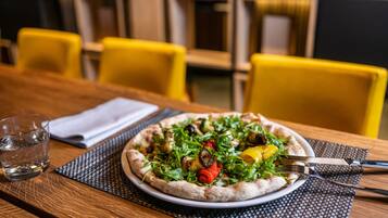 A pizza on a plate with a fork and knife on a table.