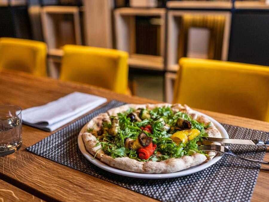 A pizza on a plate with a fork and knife on a table.