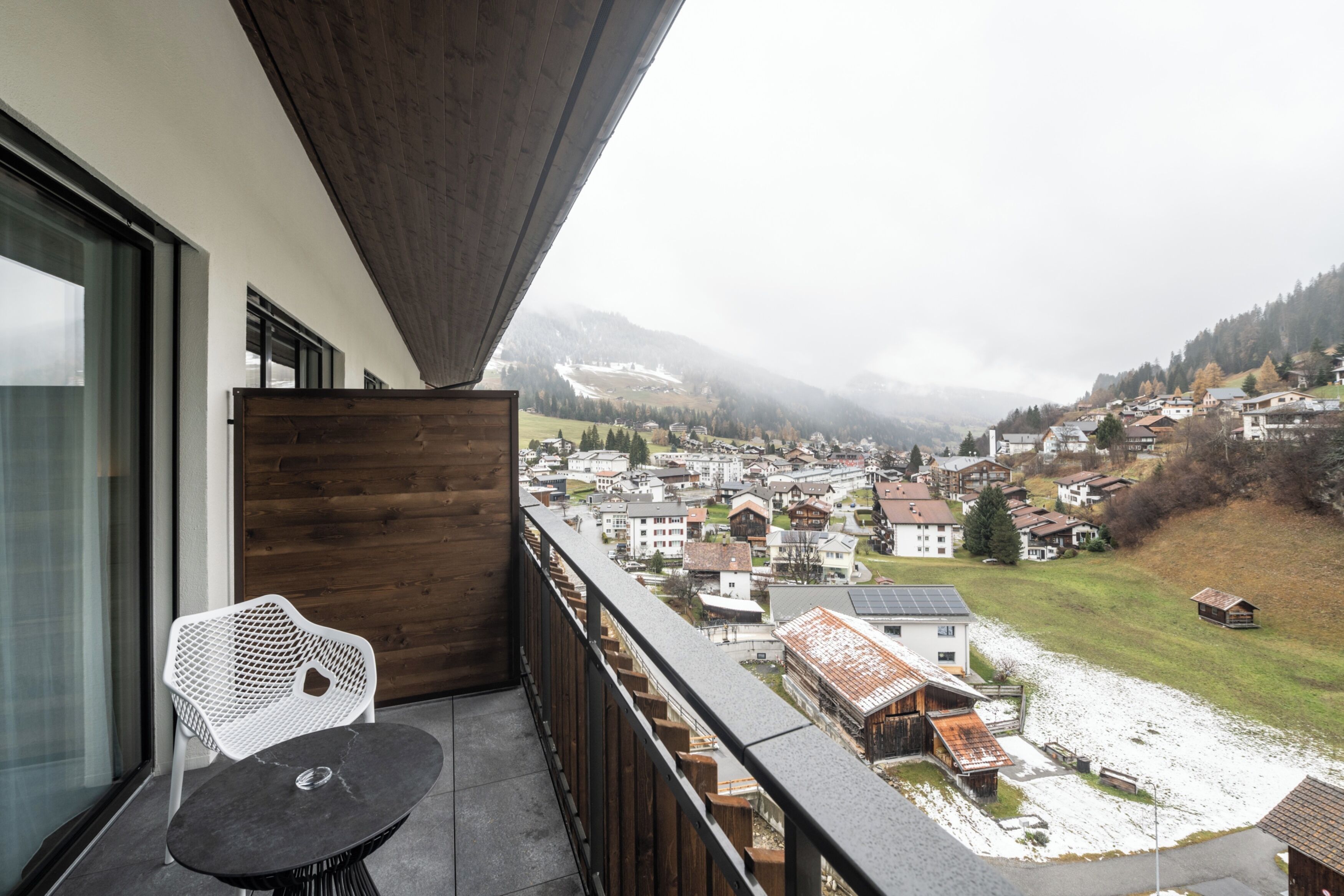 A balcony with a view of a town and mountains.