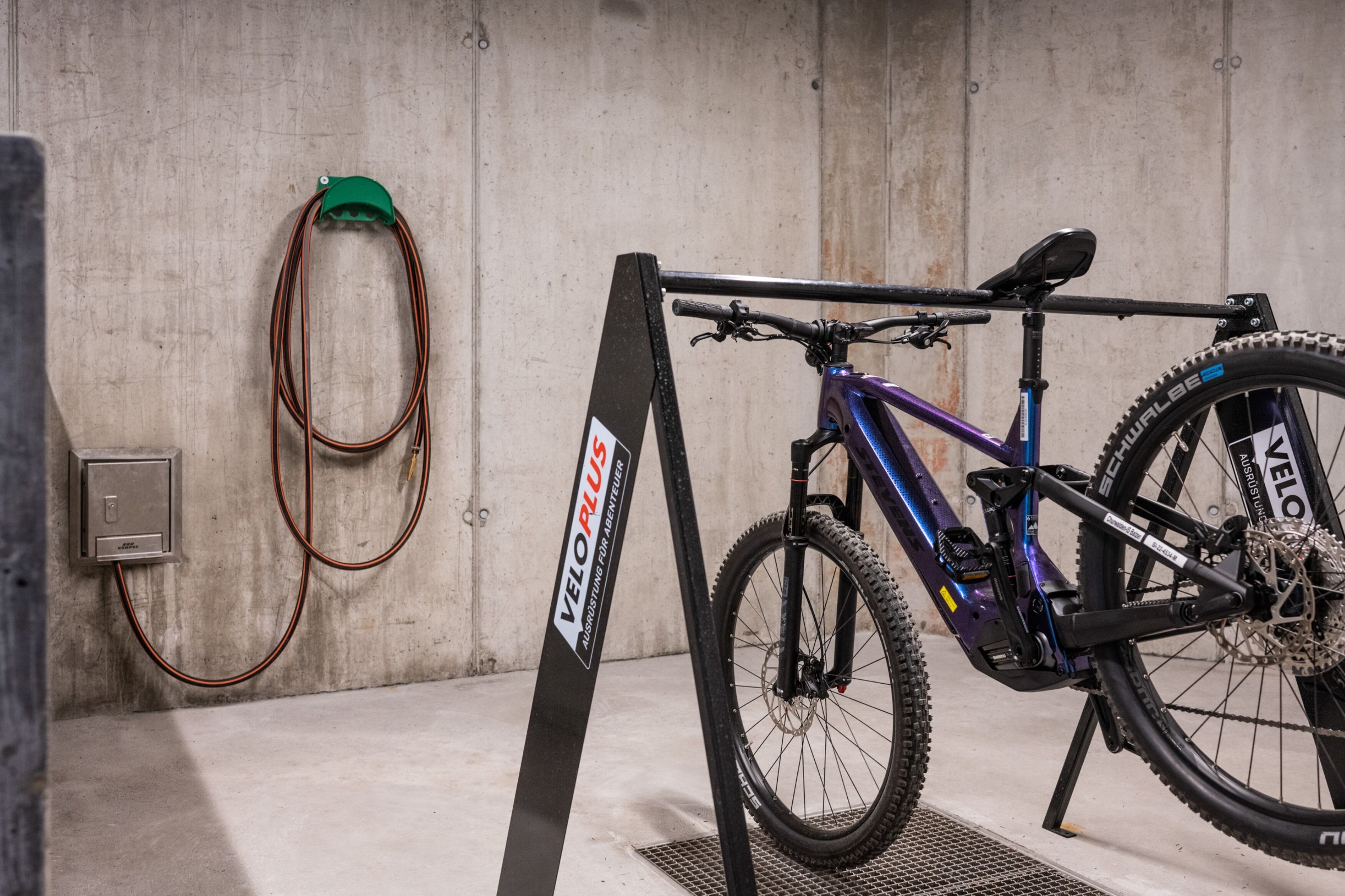 Uma bicicleta estacionada em uma garagem com parede de concreto e suporte de metal.
