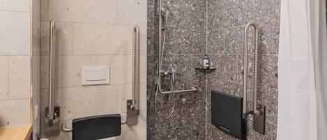 Un baño moderno con ducha, inodoro y barras de apoyo.