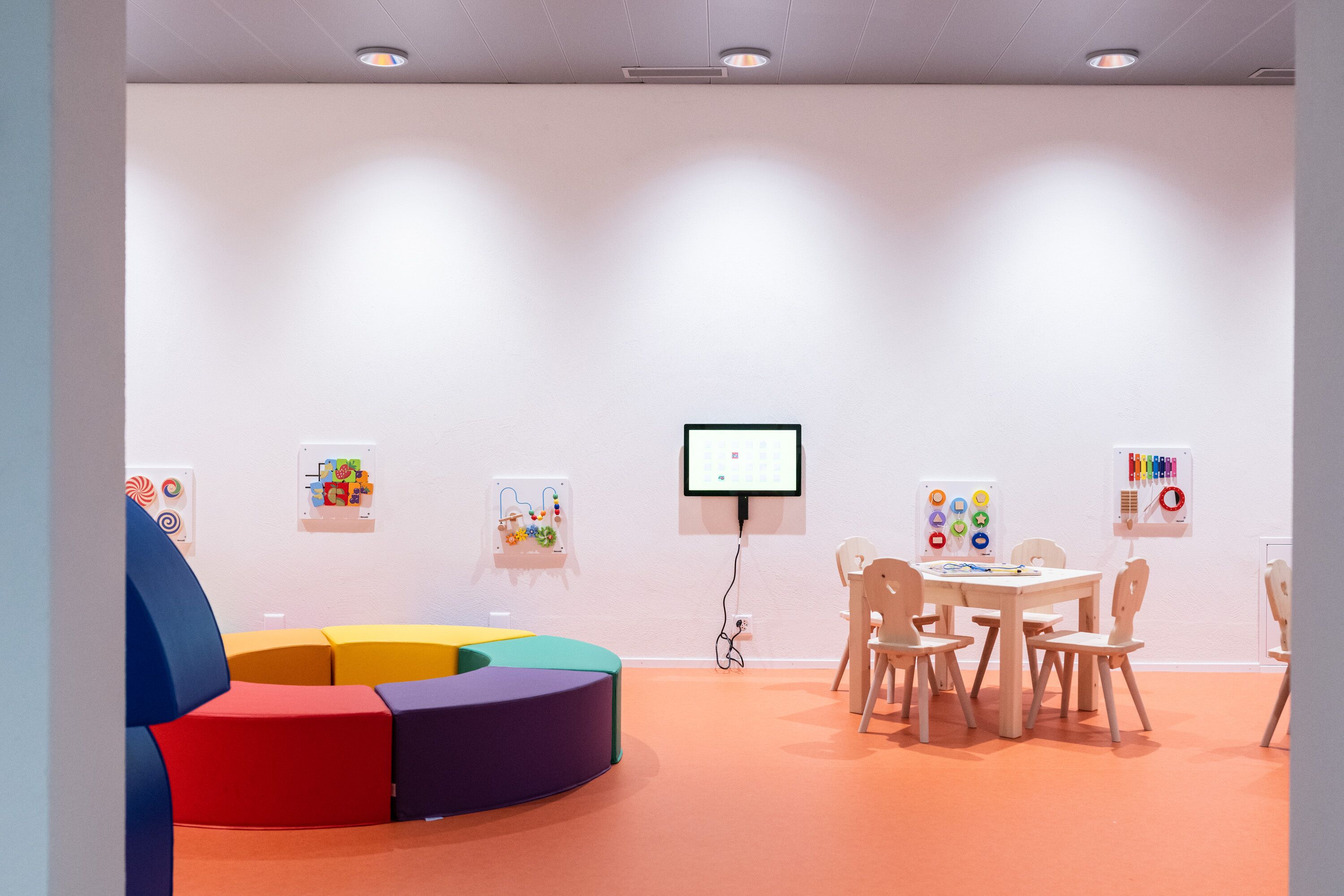 Een kamer met een witte muur, een whiteboard en een tafel met stoelen.