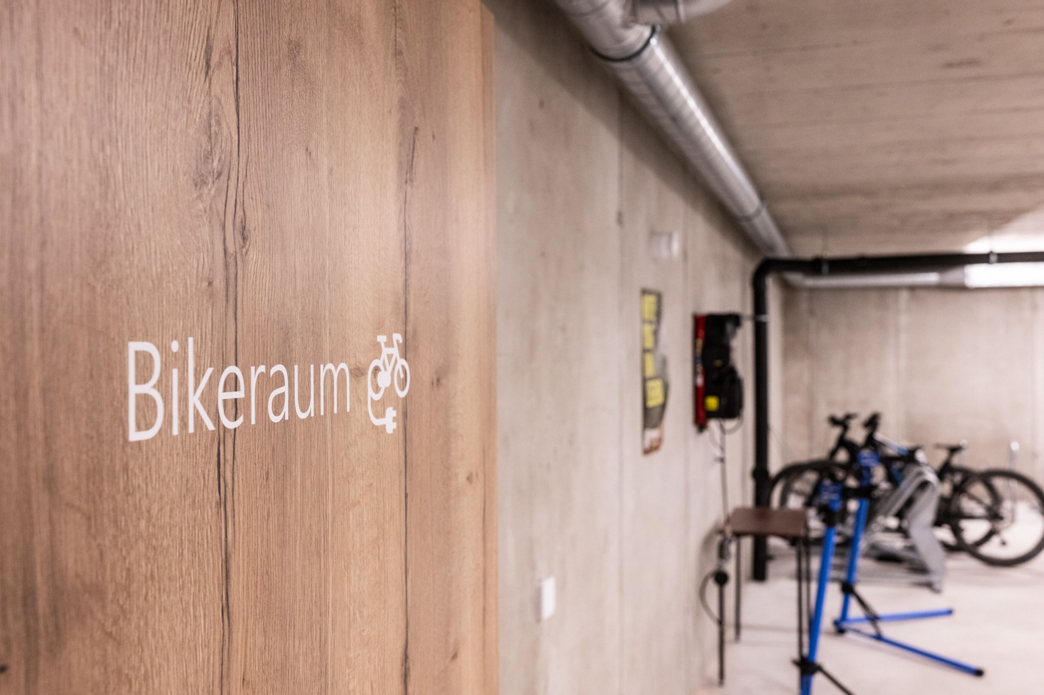 A wooden wall with the text "Bikeraum" and a bicycle symbol, indicating a bike parking area.