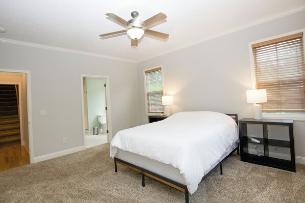 A bedroom with a bed, a nightstand, a ceiling fan, and a window with blinds. - A Pinehurst Getaway – Games, Golf & More! - 4BR/3BA Sleeps 8 (Pinehurst)