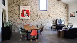 Un coin repas agrémenté d’un mur en pierre rustique, d’une table en bois et de chaises colorées.