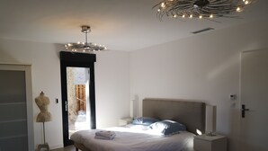 Une chambre à coucher comprenant un lit, des tables de chevet, une armoire et un luminaire au plafond.