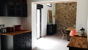 Une cuisine moderne avec des meubles de couleur sombre, un plan de travail en bois et un mur en pierre en arrière-plan.
