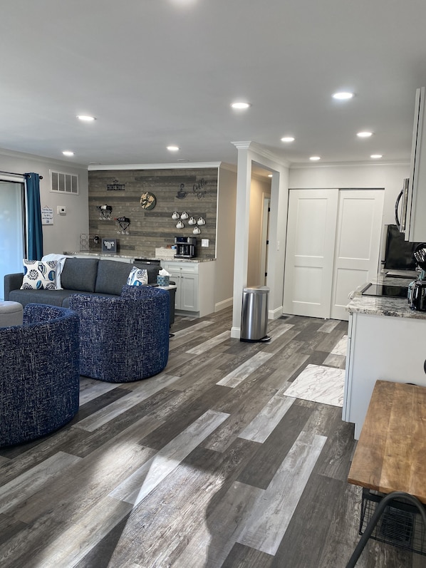 A modern living room with a gray sectional sofa, a coffee table, and a dining area with a wooden table.