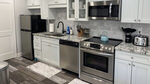 Una cocina moderna con armarios blancos, electrodomésticos de acero inoxidable, un microondas, un tostador y un hervidor.