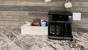 Una pared decorada con motivos de café, un reloj, tazas y una cafetera.