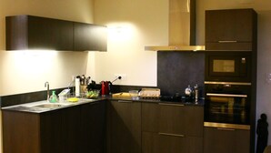 Una cocina compacta con muebles oscuros, un microondas y un lavamanos.