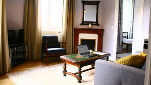 Una sala de estar con televisor, una laptop sobre una mesa de centro, un sofá y una chimenea.
