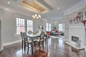Un amplio salón con una mesa de comedor, sillas, chimenea y ventanas grandes.