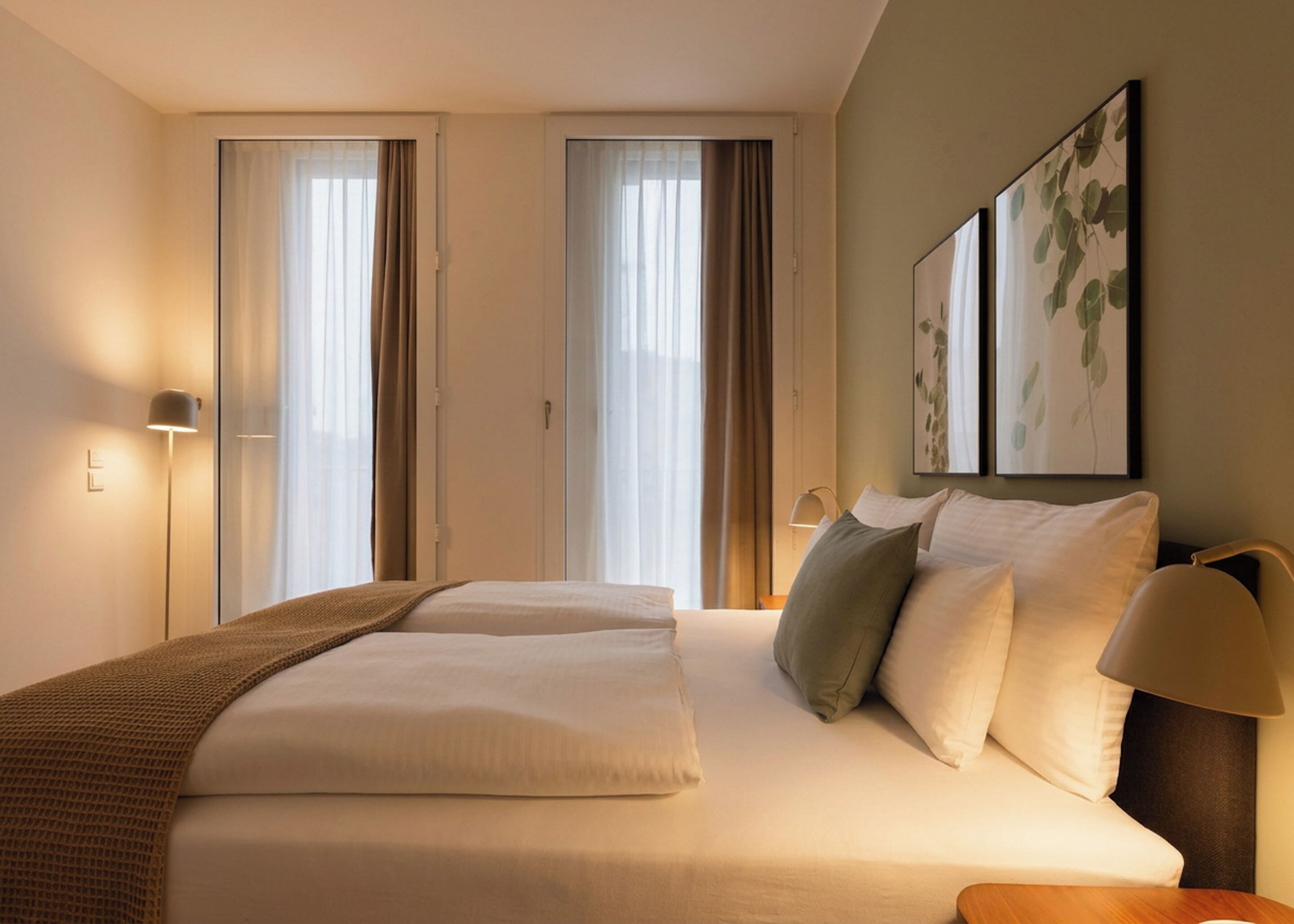 A hotel room with a large bed, two bedside tables, a lamp, and a painting on the wall.