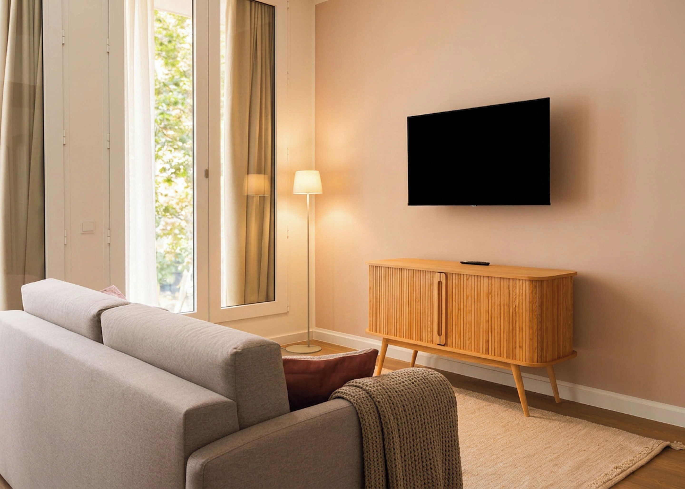 A modern living room with a sofa, a wooden cabinet, a TV, and a floor lamp.
