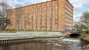 A large brick building with multiple windows and a small bridge over a canal. - Limehome Berlin Müllerstraße (Berlin)