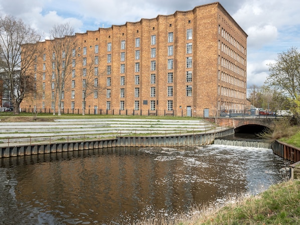 A large brick building with multiple windows and a small bridge over a canal.