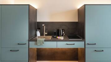 A kitchenette with a sink, coffee maker, and tea kettle.