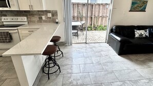 Una cocina moderna con una isla grande, taburetes de bar y un comedor con mesa y sillas.