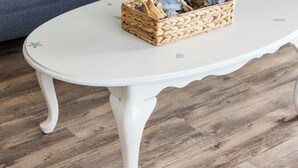 Un salon chaleureux avec un canapé blanc, des coussins à rayures et un panier en osier posé sur une table blanche.