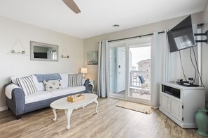 Een woonkamer met een bank, salontafel en een tv op een kast.