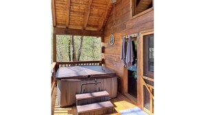A wooden cabin with a hot tub, a ceiling fan, and a view of the forest. - Original Log Cabin, Private, Secluded, Mt views, Hot Tub, Honeymoon/Anniversary! (Gatlinburg)
