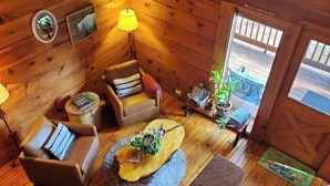A cozy cabin interior with a wooden floor, a sofa, a coffee table, and a lamp. - Original Log Cabin, Private, Secluded, Mt views, Hot Tub, Honeymoon/Anniversary! (Gatlinburg)