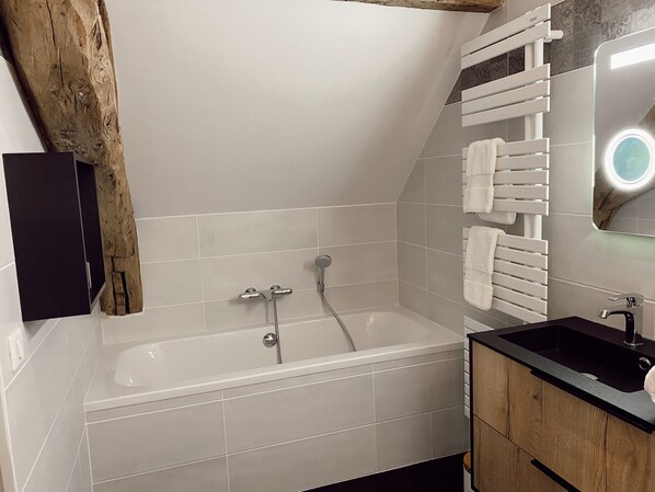 A modern bathroom with a bathtub, a wooden vanity, and a towel rack. - Manoir de Villamont (Savigny-les-Beaune)