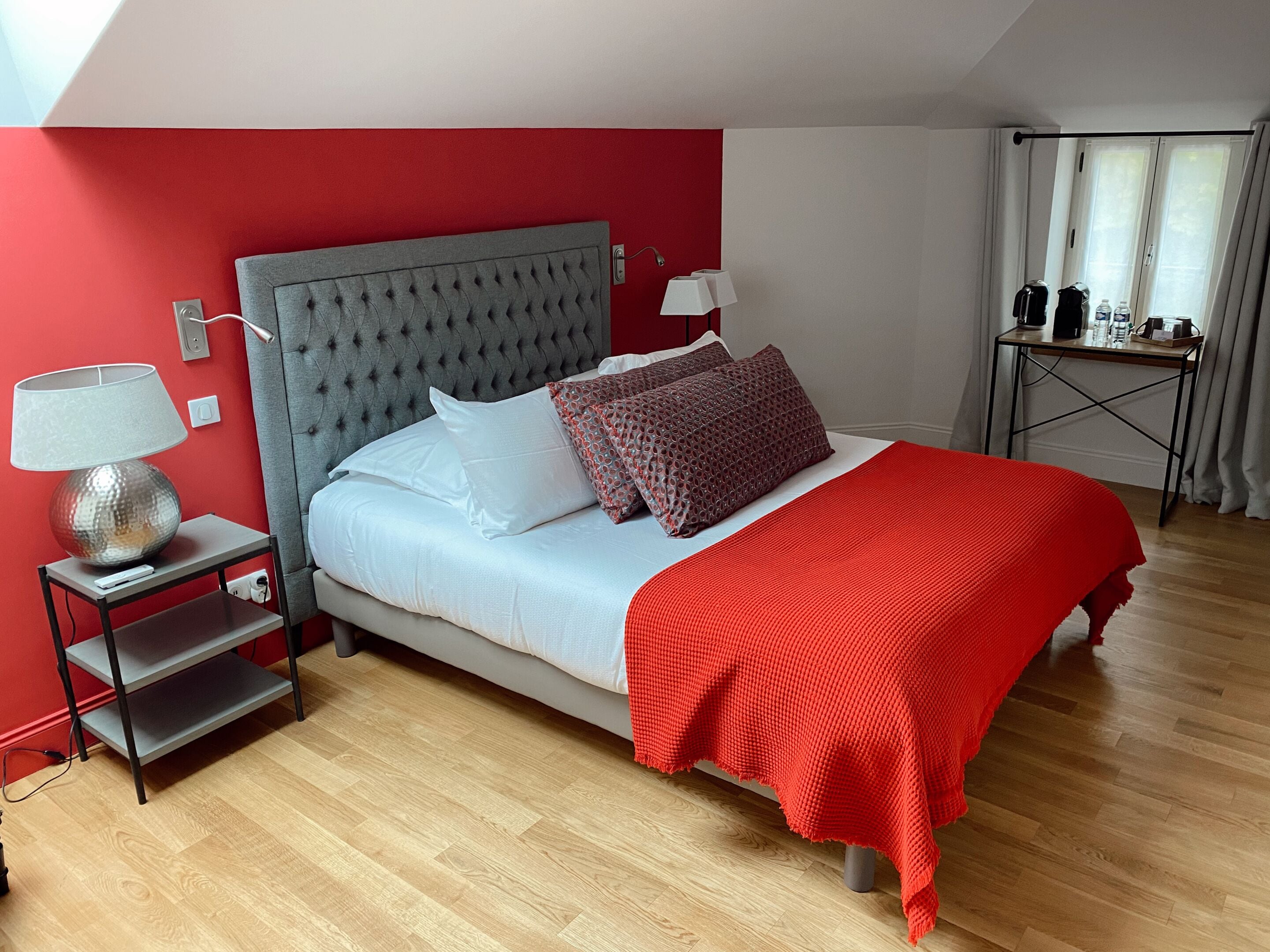 Un dormitorio ordenado con cama, mesitas de noche, lámpara y una mesa de centro.