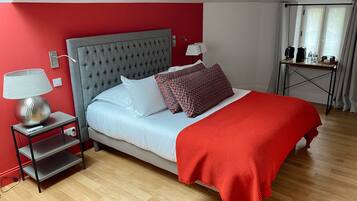 Un dormitorio ordenado con cama, mesitas de noche, lámpara y una mesa de centro.