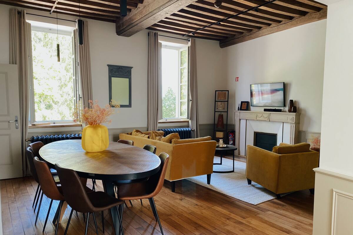 A dining area with a round table and chairs, a sofa, and a fireplace.