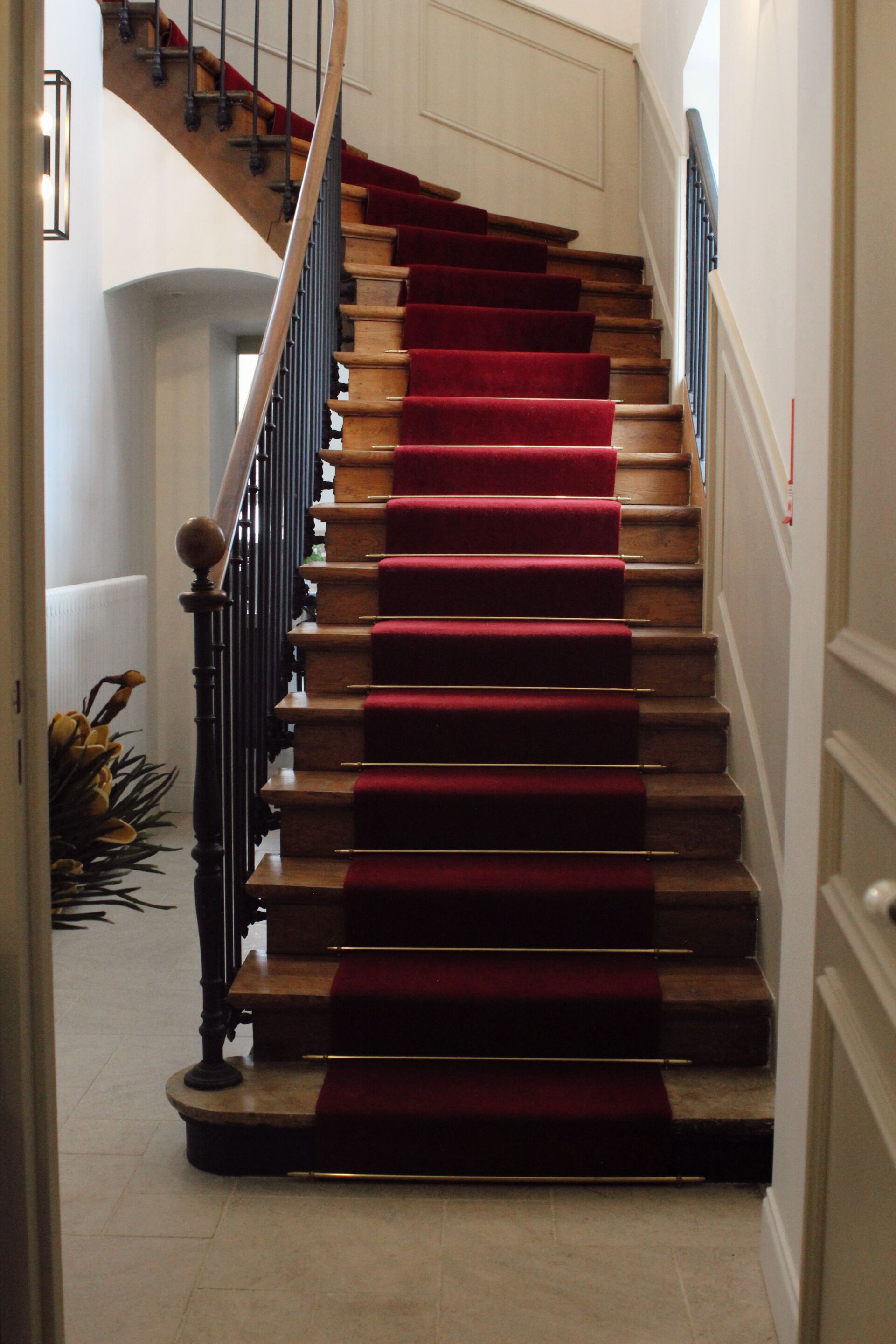 Una escalera con peldaños alfombrados de rojo y barandilla de madera.