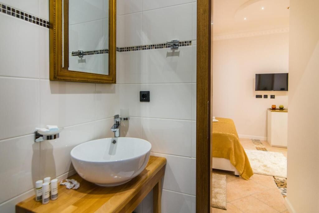 A bathroom with a white sink, a mirror, and a wooden vanity.