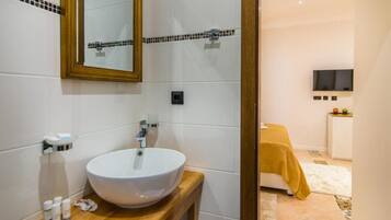A bathroom with a white sink, a mirror, and a wooden vanity.