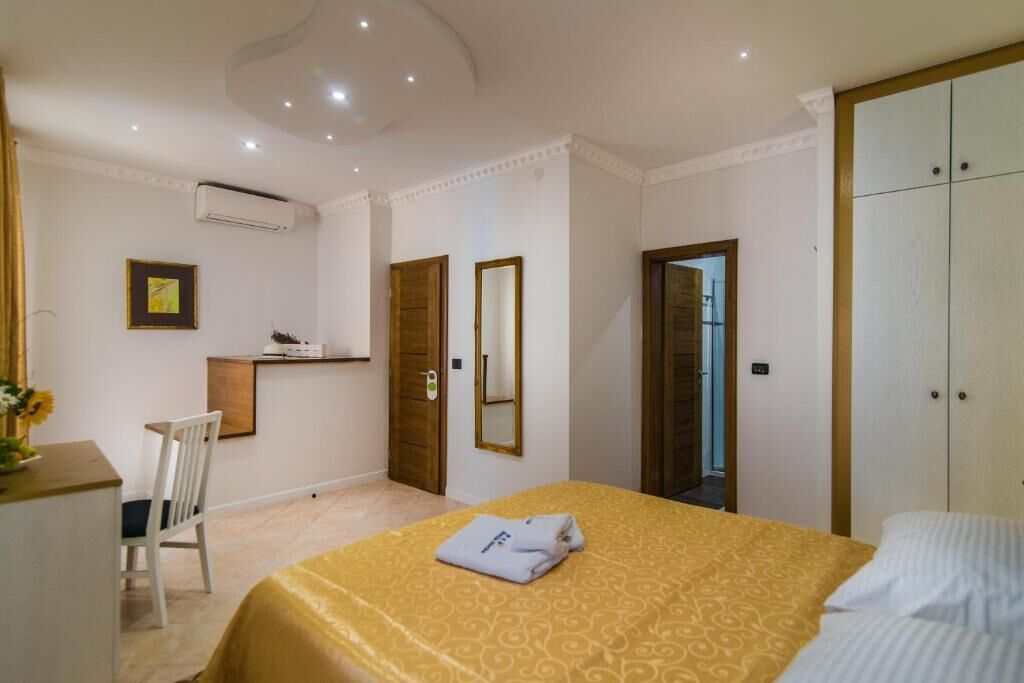 Een hotelkamer met een bed, bureau, stoel, kledingkast en spiegel.