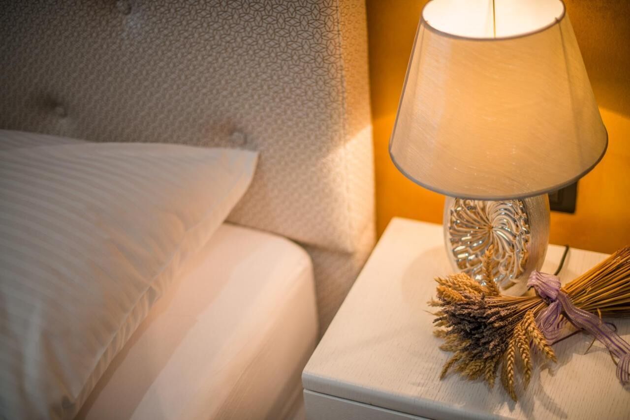 A neatly made bed with a white pillow and a lamp on a bedside table.