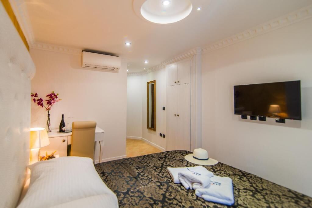 Una habitación de hotel con cama, escritorio, silla, televisor y armario.